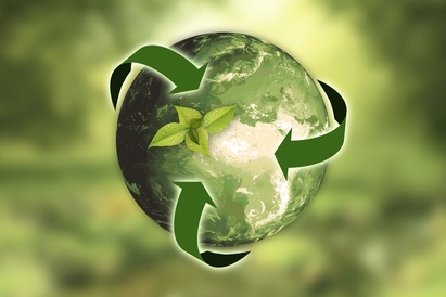 Hand holding the Earth with green recycling arrows representing sustainability