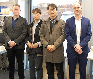 Four men standing posing for a group photo at the Cambridge Graphene Centre