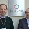 Two men standing in front of a building name sign.