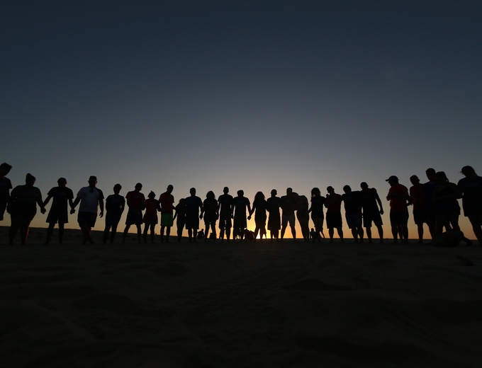 Team of people shown as shadow outlines with a twilight sky behind them